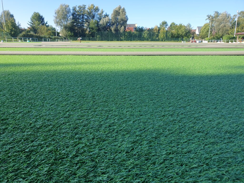 Ein Sportplatz, auf dem gerade ein neuer Kunstrasen ausgerollt wird