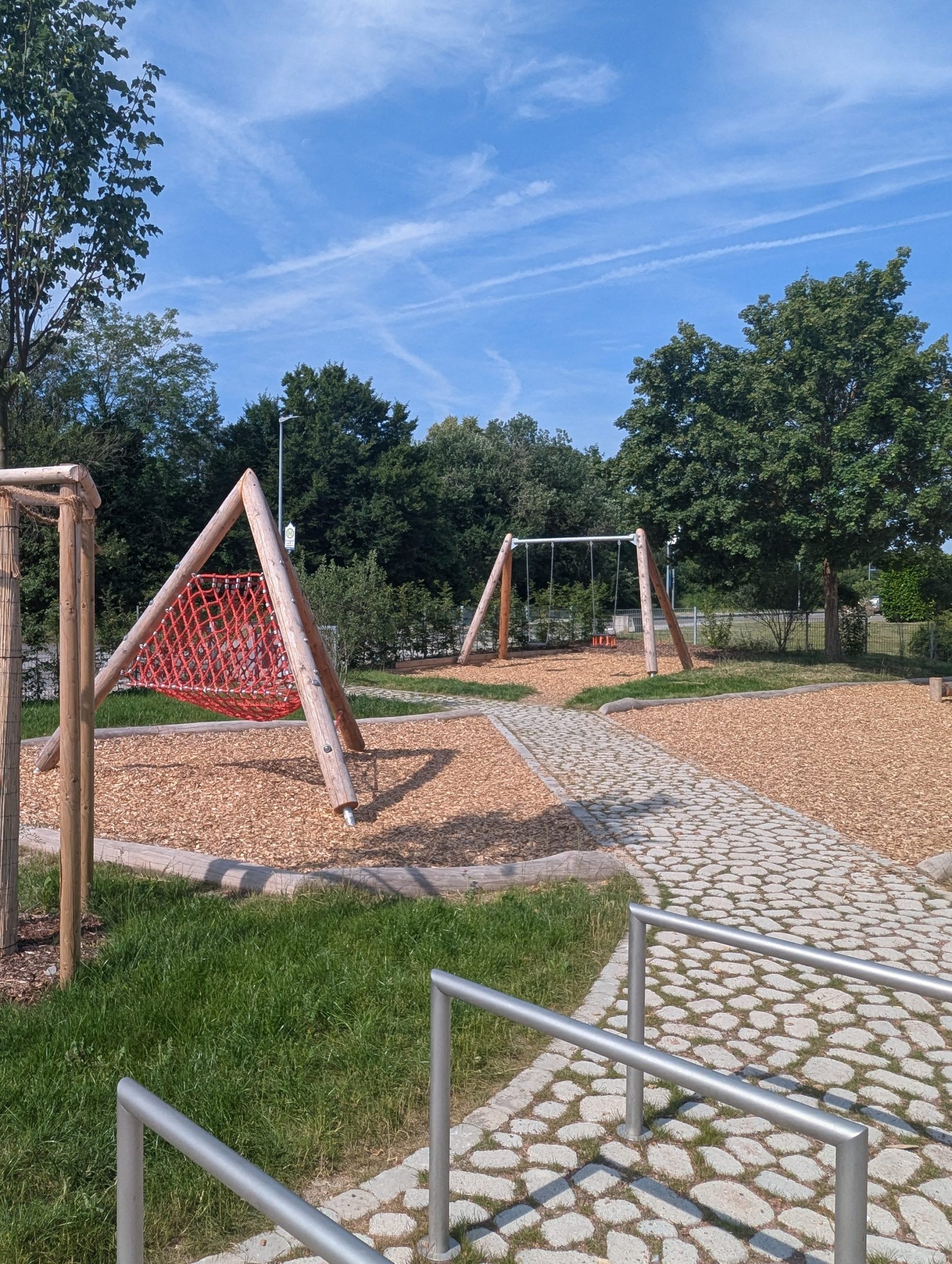 Spielbereich des neu eröffneten Quartiersplatzes in Singen mit Klettergerüst und Schaukel aus Robinienholz, umgeben von Holzhackschnitzeln und begrünten Pflasterwegen – ein Ort für Bewegung, Spiel und Begegnung.